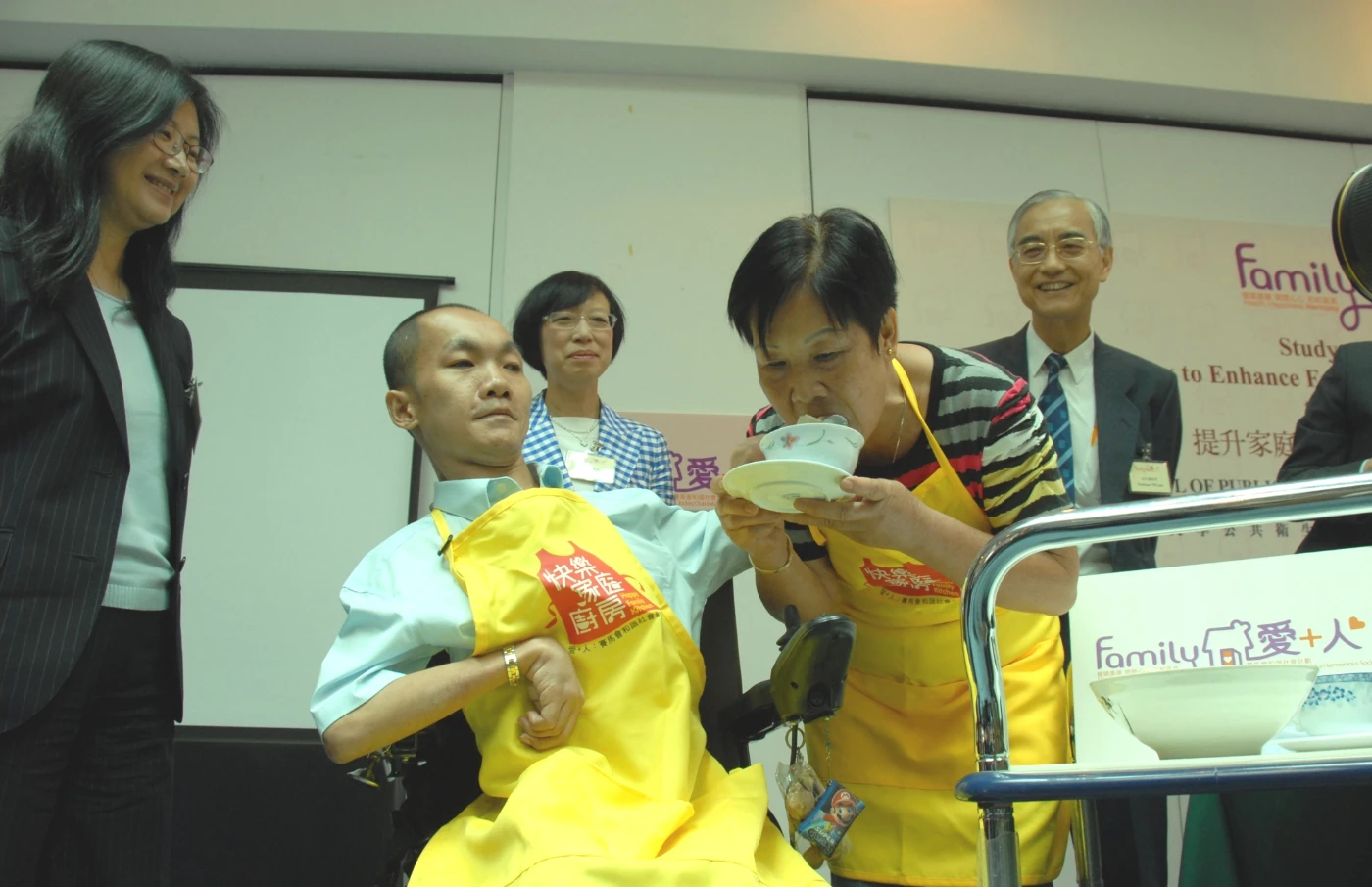 鄧志英先生(身穿黃色圍裙)參與「快樂家庭廚房」計劃後學懂對家人表達關心，活動上更餵母親鄧太吃親手包的餃子，以表對母親的關懷。