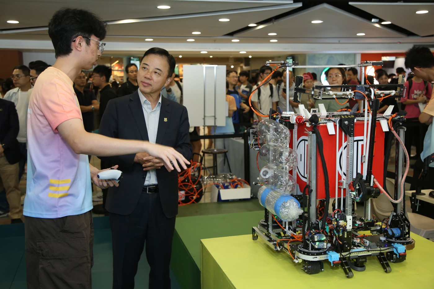 Professor Xiang Zhang, President and Vice-Chancellor of HKU, speaks to a member of the University's championship-winning Robocon team at IDay 2026.